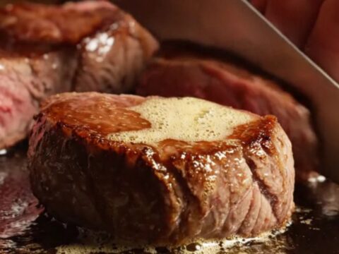 A close-up of perfectly seared venison medallions glistening with a truffle honey glaze.