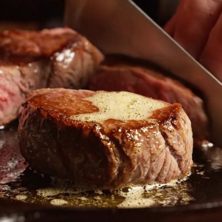 A close-up of perfectly seared venison medallions glistening with a truffle honey glaze.