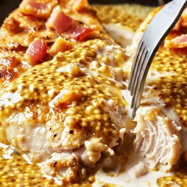 A close-up of a golden-seared chicken breast cutlet coated in a creamy honey mustard sauce with crispy bacon.