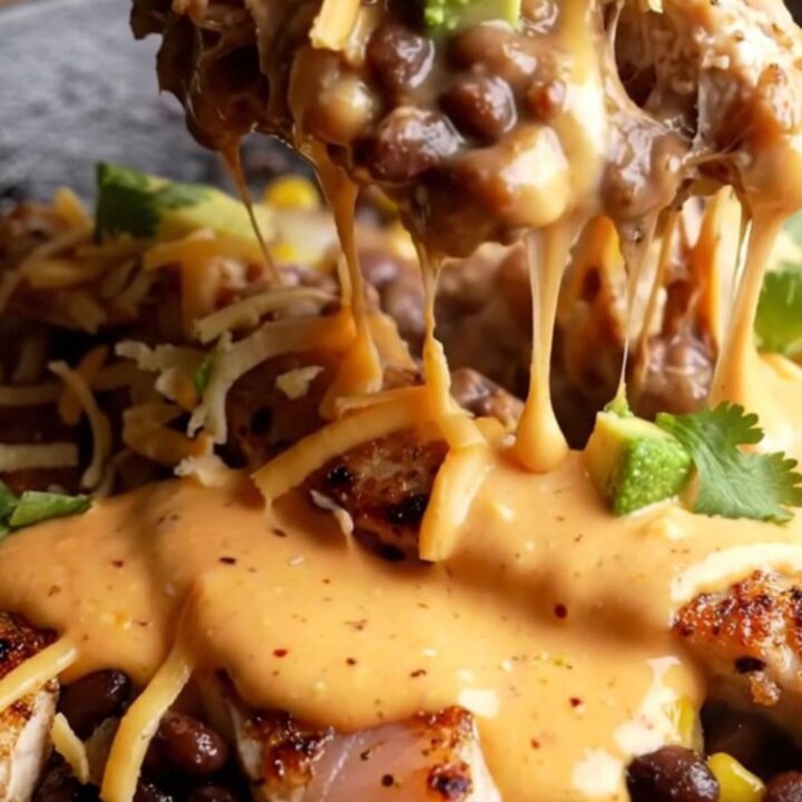 A cast iron skillet filled with blackened chicken strips, black beans, corn, and melted cheese
