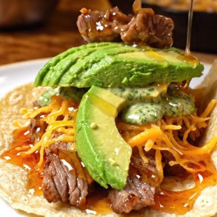 A close-up shot of a chipotle honey flank steak taco with a golden crispy Oaxaca cheese crust.