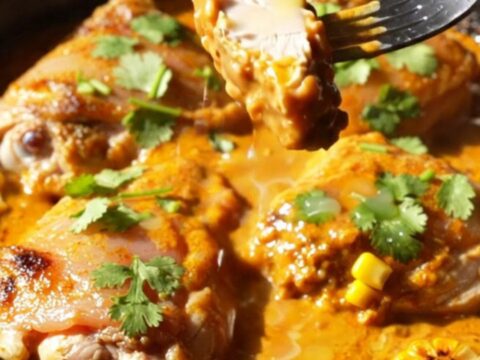 A cast iron skillet filled with crispy golden-brown chicken thighs, charred corn