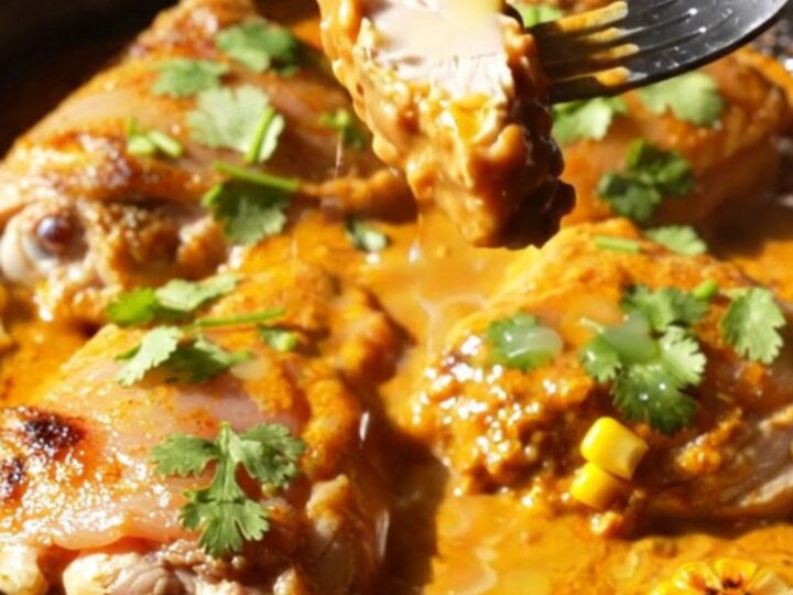 A cast iron skillet filled with crispy golden-brown chicken thighs, charred corn