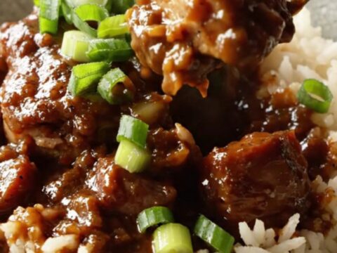 A cast iron skillet filled with Cajun blackened chicken, sliced Andouille sausage, and a rich, dark sauce.