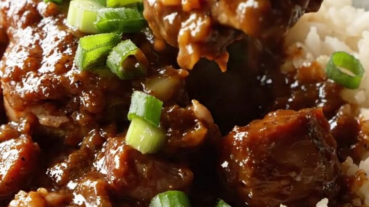 A cast iron skillet filled with Cajun blackened chicken, sliced Andouille sausage, and a rich, dark sauce.
