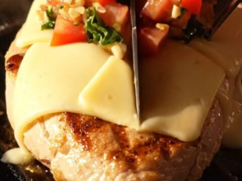 A close-up shot of grilled chicken breasts topped with melted provolone cheese and fresh tomato bruschetta in a cast-iron