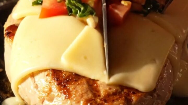 A close-up shot of grilled chicken breasts topped with melted provolone cheese and fresh tomato bruschetta in a cast-iron