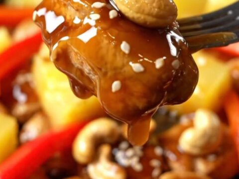 A cast-iron skillet filled with glossy teriyaki chicken, charred pineapple, and toasted cashews.