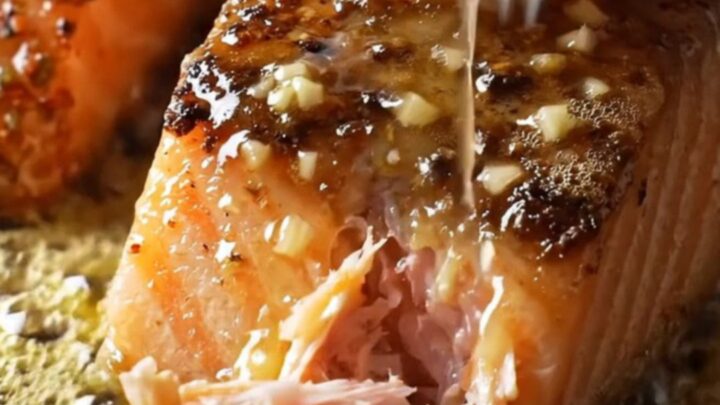 A cast-iron skillet filled with blackened salmon fillets and jumbo shrimp, glazed in a shimmering honey-garlic sauce.