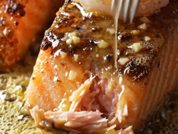 A cast-iron skillet filled with blackened salmon fillets and jumbo shrimp, glazed in a shimmering honey-garlic sauce.
