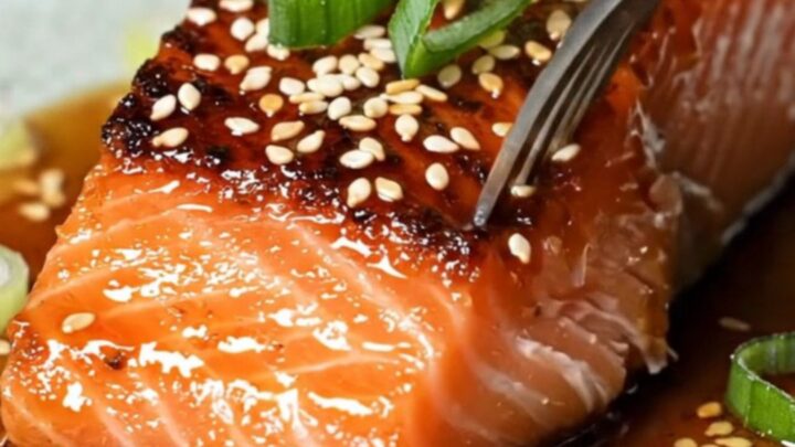 Sticky gochujang maple glazed salmon fillets with crispy blistered skin, garnished with sesame seeds and scallion curls.