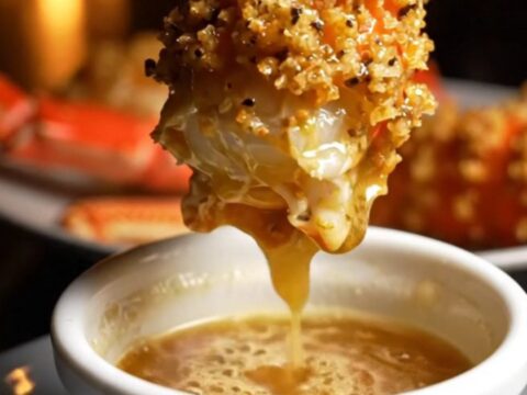 Close-up of butter-drenched Alaskan King Crab legs in a cast-iron skillet with a golden parmesan crust.