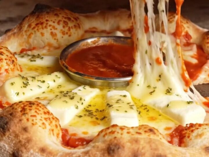 A close-up of a golden brown stuffed crust pizza ring with a molten mozzarella pull.