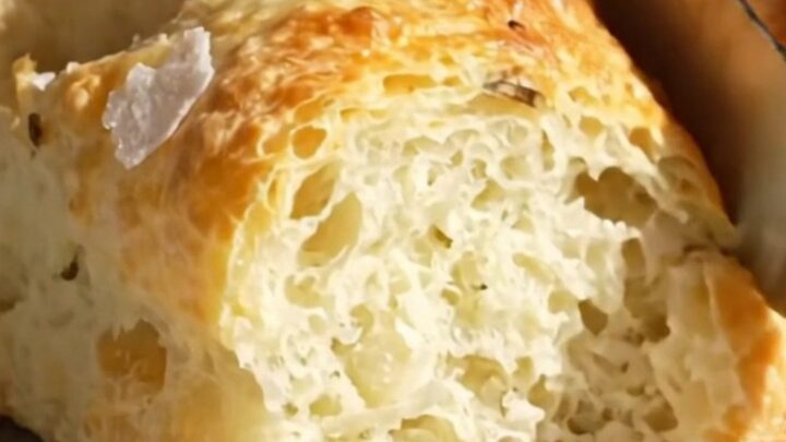 A close-up shot of a freshly baked rosemary focaccia with visible air bubbles and a golden, crispy crust.