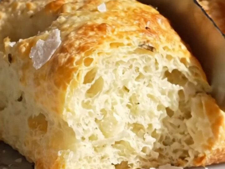 A close-up shot of a freshly baked rosemary focaccia with visible air bubbles and a golden, crispy crust.