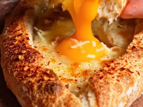 A freshly baked Turkish pide boat filled with melted kasseri cheese and a golden, runny egg yolk.