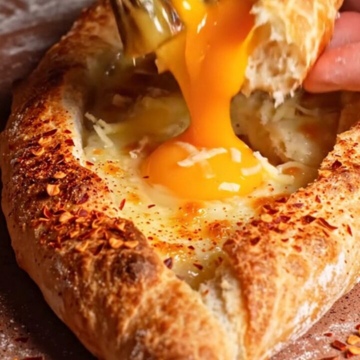 A freshly baked Turkish pide boat filled with melted kasseri cheese and a golden, runny egg yolk.