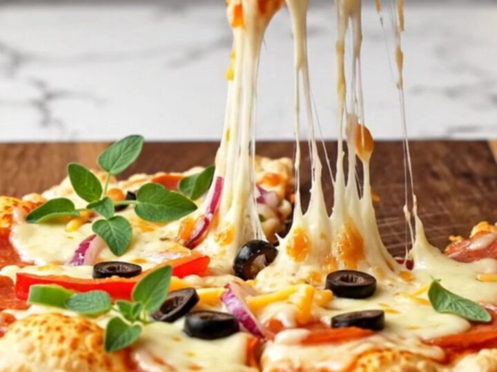 A crispy double-stack supreme tortilla pizza sliced on a wooden board with fresh oregano.
