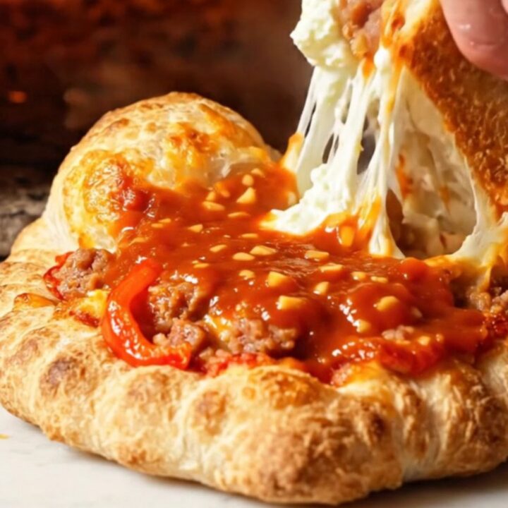 A golden-brown crispy calzone sliced open to reveal a steaming, cheesy ricotta and sausage filling.