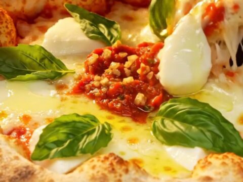 A crispy, square-cut Sicilian Grandma-style pizza with a golden, fried crust, melted mozzarella, and fresh basil leaves.