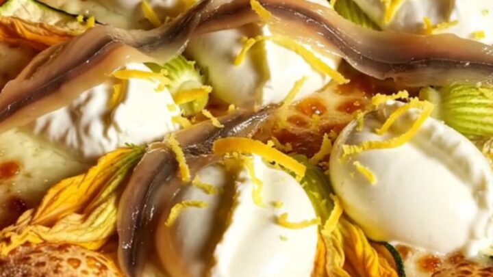 A close-up of a Roman pizza bianca with zucchini blossoms and creamy cheese, showing a perfect airy crust.