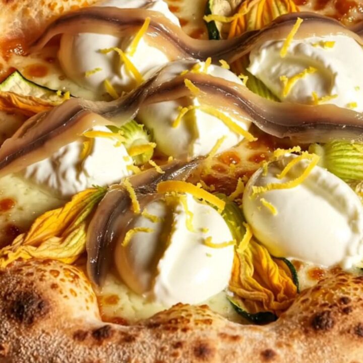 A close-up of a Roman pizza bianca with zucchini blossoms and creamy cheese, showing a perfect airy crust.