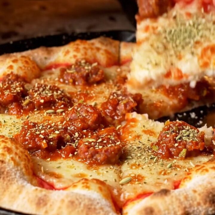 A close-up shot of a square-cut tavern-style pizza showing a thin, crispy crust topped with fennel sausage.