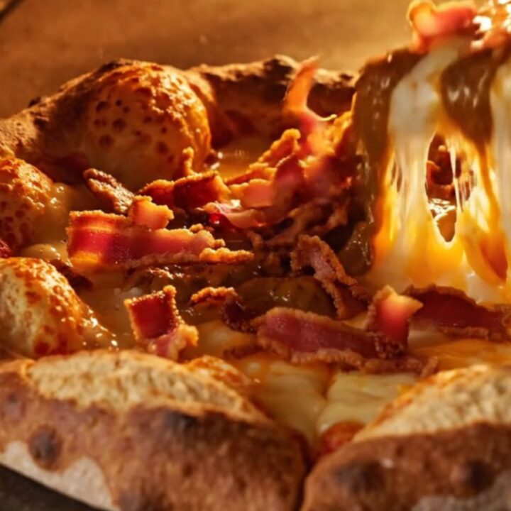 A close-up of a cheddar stuffed pretzel crust pizza slice being pulled away, showing molten cheese.