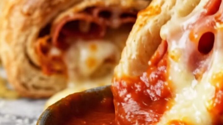 A close-up of a braided Italian stromboli ring, golden brown and sliced to show layers of salami and melted cheese.