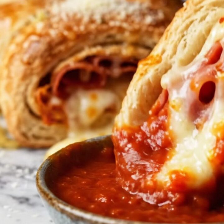 A close-up of a braided Italian stromboli ring, golden brown and sliced to show layers of salami and melted cheese.