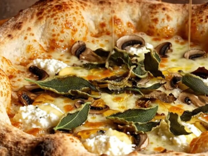 A close-up of a truffle ricotta stuffed crust pizza with mushrooms, melted fontina, and a drizzle of honey.