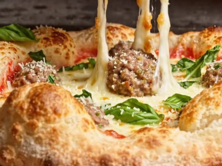 A close-up of a meatball-stuffed crown crust pizza with a rich vodka sauce center.