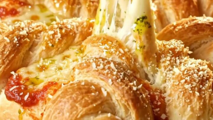 A golden-brown pull-apart pepperoni pizza star bread displayed on a rustic wooden board.