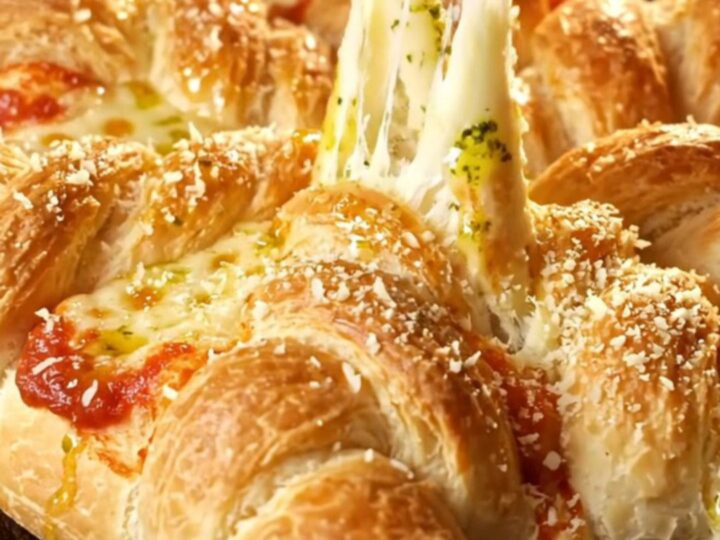 A golden-brown pull-apart pepperoni pizza star bread displayed on a rustic wooden board.