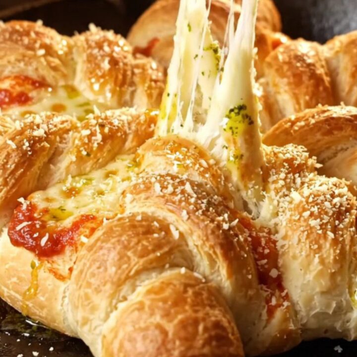 A golden-brown pull-apart pepperoni pizza star bread displayed on a rustic wooden board.