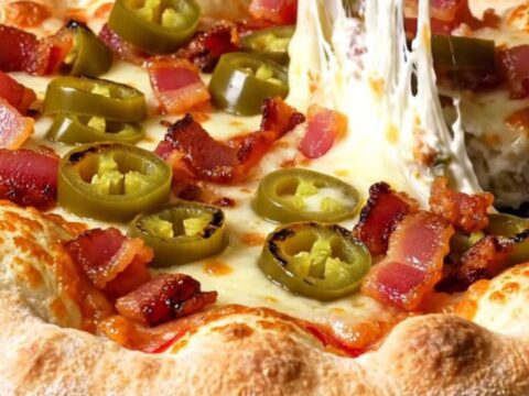 A close-up of a stuffed crust pizza with a molten cream cheese and jalapeño filling being pulled apart.
