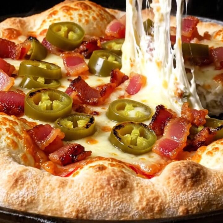 A close-up of a stuffed crust pizza with a molten cream cheese and jalapeño filling being pulled apart.