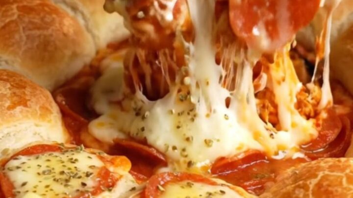 A cast-iron skillet filled with a bubbling cheesy marinara dip surrounded by golden mozzarella-stuffed breadsticks.