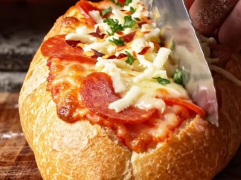 A crispy, golden-brown stuffed pizza baguette boat sliced into thick rounds with melted mozzarella and pepperoni.