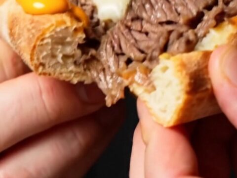 A close-up shot of a Philly cheesesteak stuffed crust pizza showing the melted cheese and ribeye inside the crust.