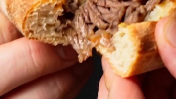A close-up shot of a Philly cheesesteak stuffed crust pizza showing the melted cheese and ribeye inside the crust.
