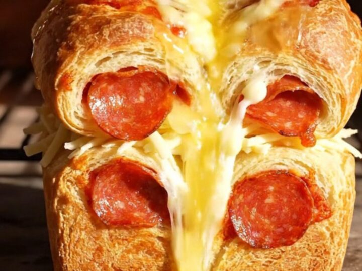 A golden, buttery pull-apart loaf with melted mozzarella and pepperoni, showing long cheese strings.