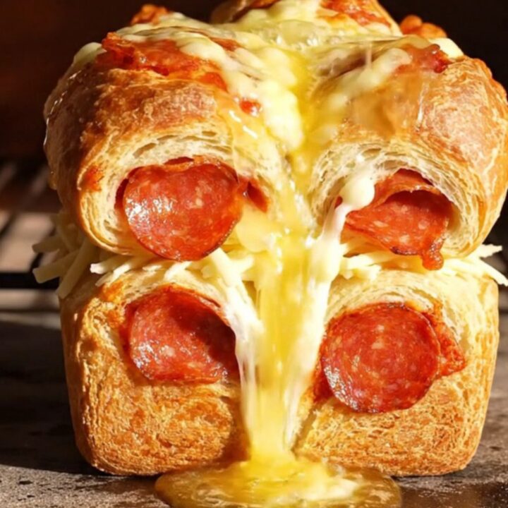 A golden, buttery pull-apart loaf with melted mozzarella and pepperoni, showing long cheese strings.