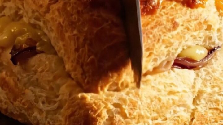 A close-up of a French onion soup focaccia with golden brown gruyere cheese being pulled apart.