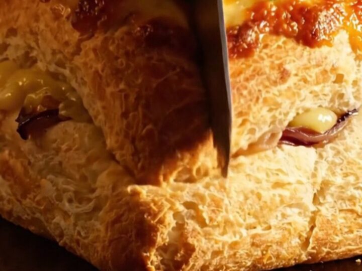 A close-up of a French onion soup focaccia with golden brown gruyere cheese being pulled apart.