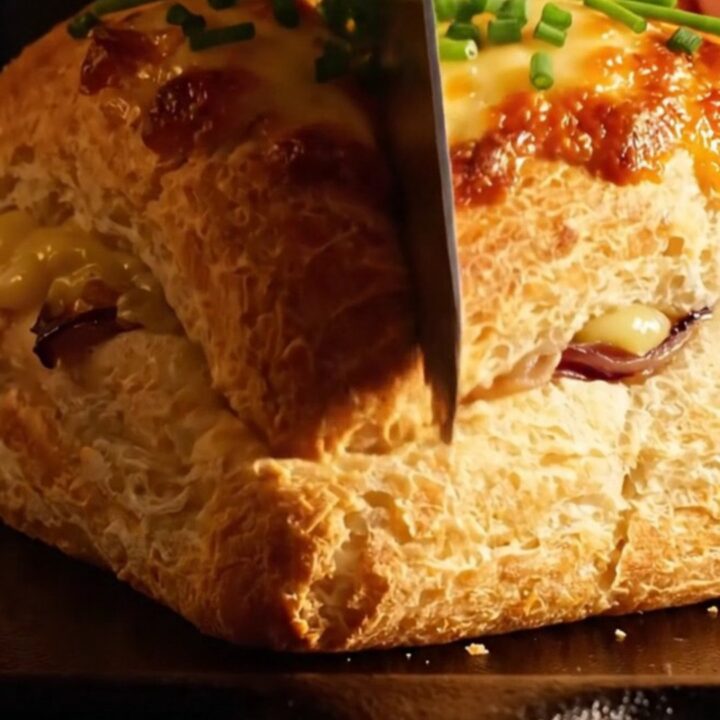 A close-up of a French onion soup focaccia with golden brown gruyere cheese being pulled apart.