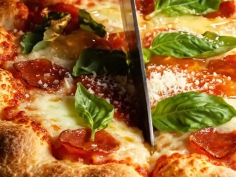 A close-up shot of a thick square of pepperoni pizza focaccia with a golden, bubbly crust and melted cheese.