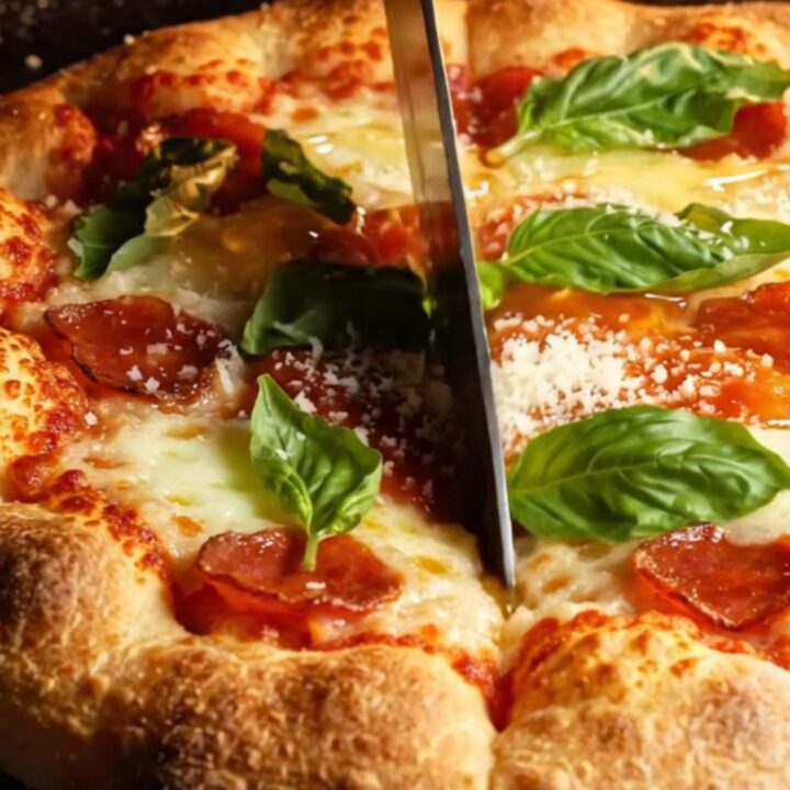 A close-up shot of a thick square of pepperoni pizza focaccia with a golden, bubbly crust and melted cheese.