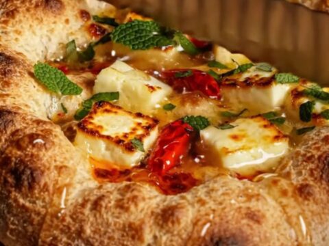 Golden, bubbly focaccia topped with blistered halloumi, vibrant red chili oil, and fresh mint.