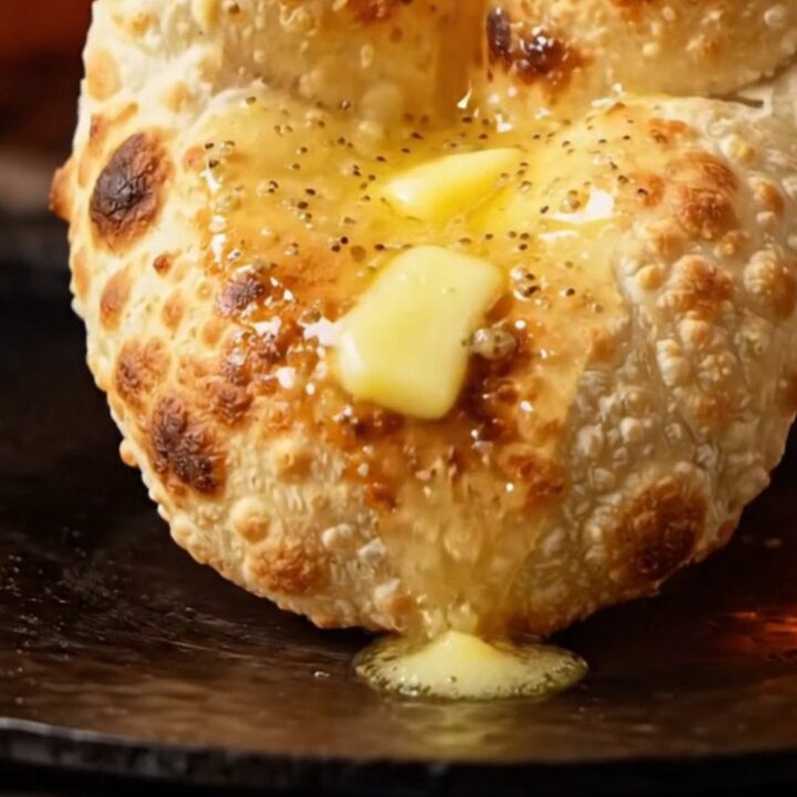 A close-up shot of a stuffed garlic cheese naan being torn open, revealing melted cheese and fresh cilantro.